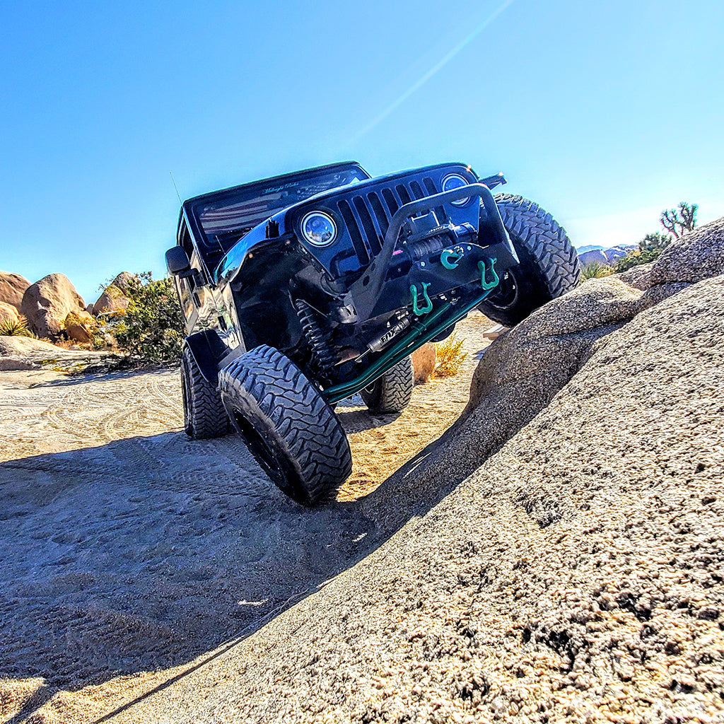 2006 Jeep Wrangler TJ flexing on a rock in Southern California with custom color matched moose knuckle shackles under winch on front bumper